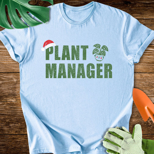 Light blue T-shirt with a Santa hat, festive plant pot, and "Plant Manager" lettering.