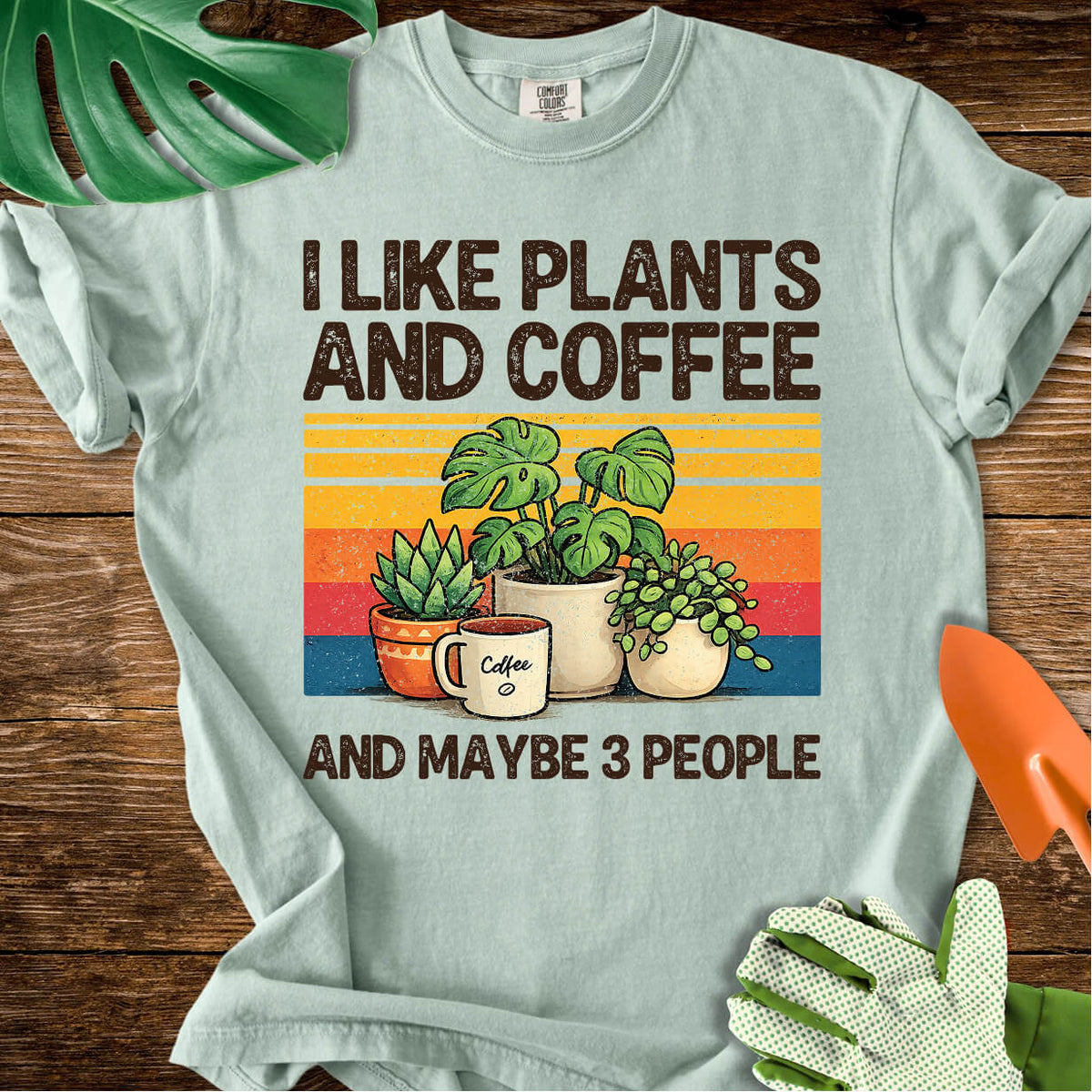 Bay sage green Comfort Colors T-shirt with plants, coffee, and retro stripes with "I Like Plants and Coffee and Maybe 3 People".