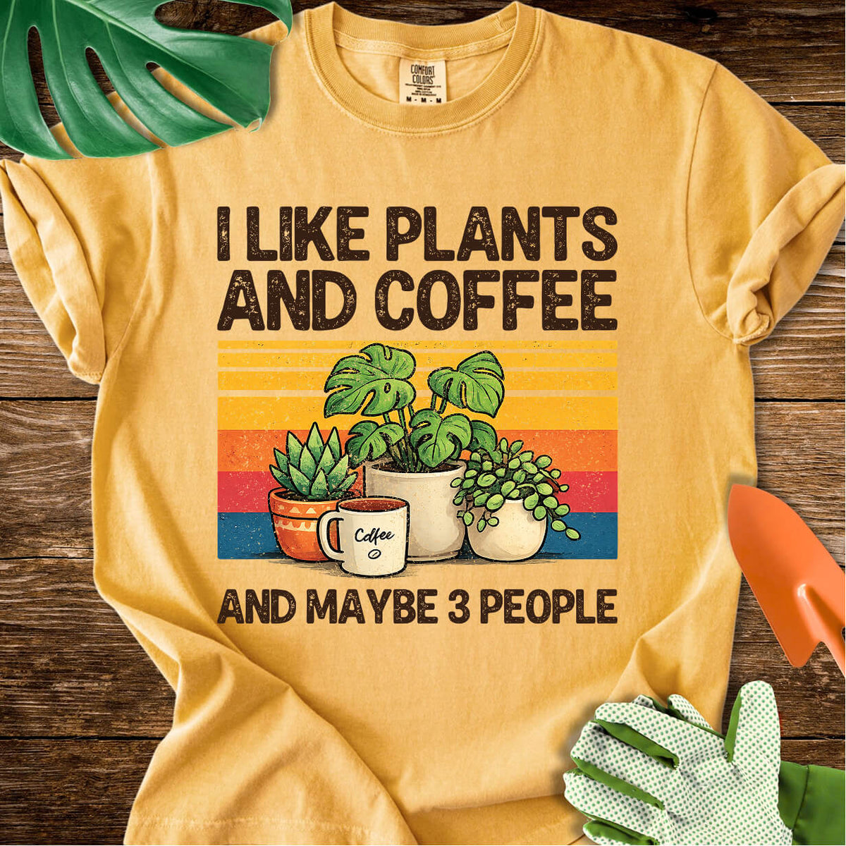 Mustard yellow Comfort Colors T-shirt with plants, coffee, and retro stripes with "I Like Plants and Coffee and Maybe 3 People".