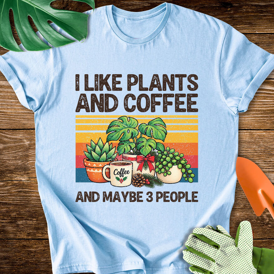 Light blue T-shirt with Christmas plants and coffee with "I Like Plants and Coffee and Maybe 3 People".
