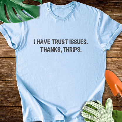 Light blue T-shirt with minimalist lettering reading "I Have Trust Issues. Thanks, Thrips.".