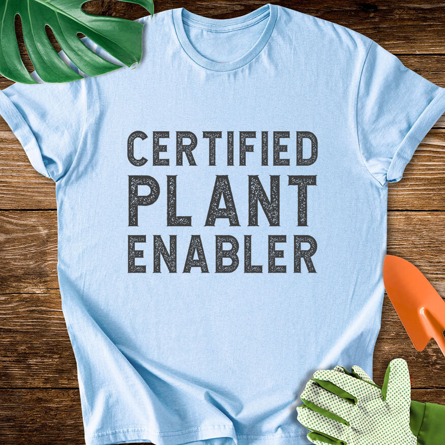 Light blue T-shirt with bold distressed lettering reading "Certified Plant Enabler".
