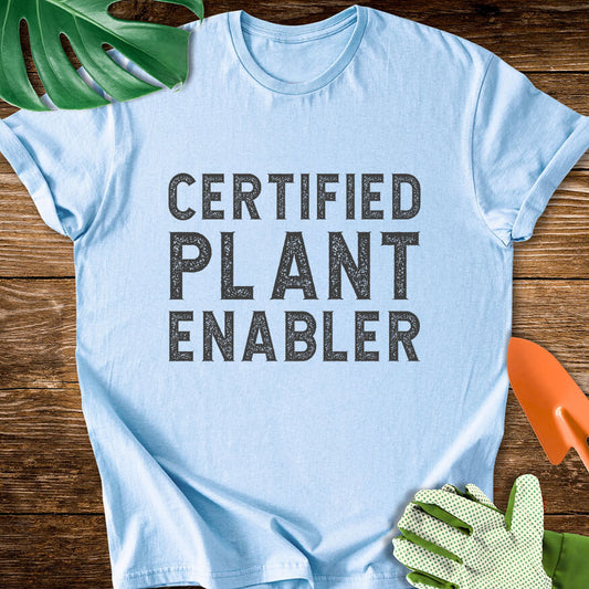 Light blue T-shirt with bold distressed lettering reading "Certified Plant Enabler".